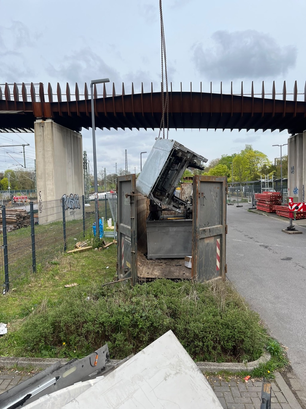 Ausgebautes Anlagenteil hängt am Kranhaken über einem Abfallcontainer